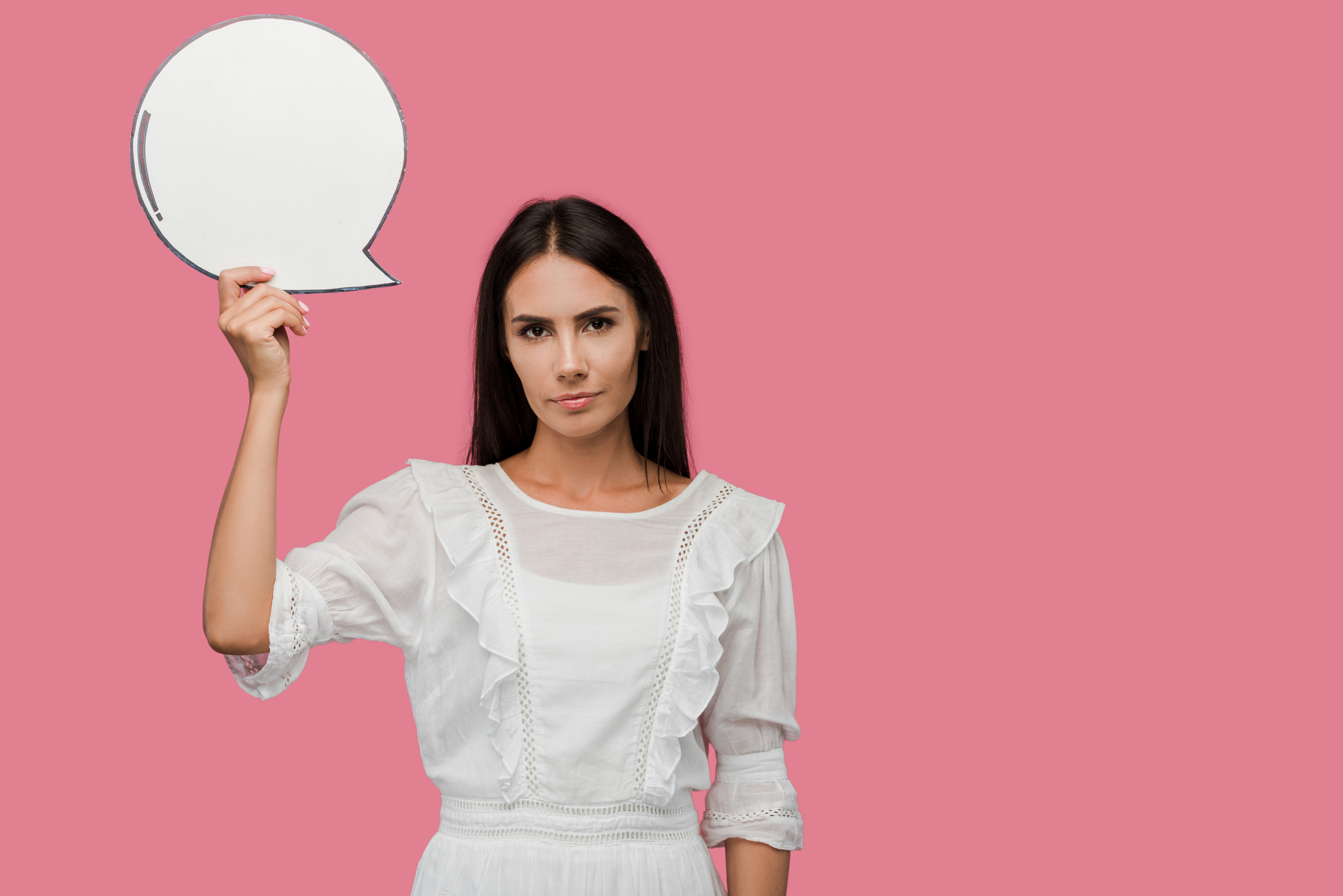 Young woman holding blank speech bubble isolated on pink