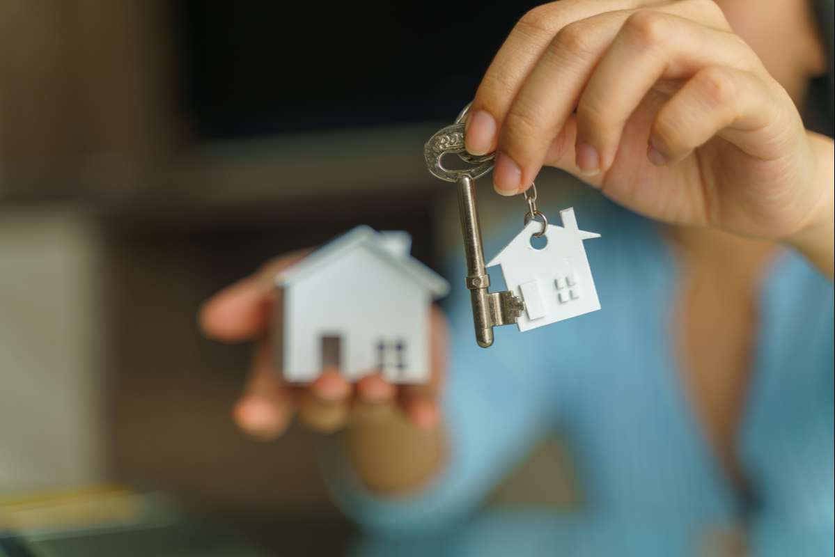 Female hand holding house key and house model (R) (S)