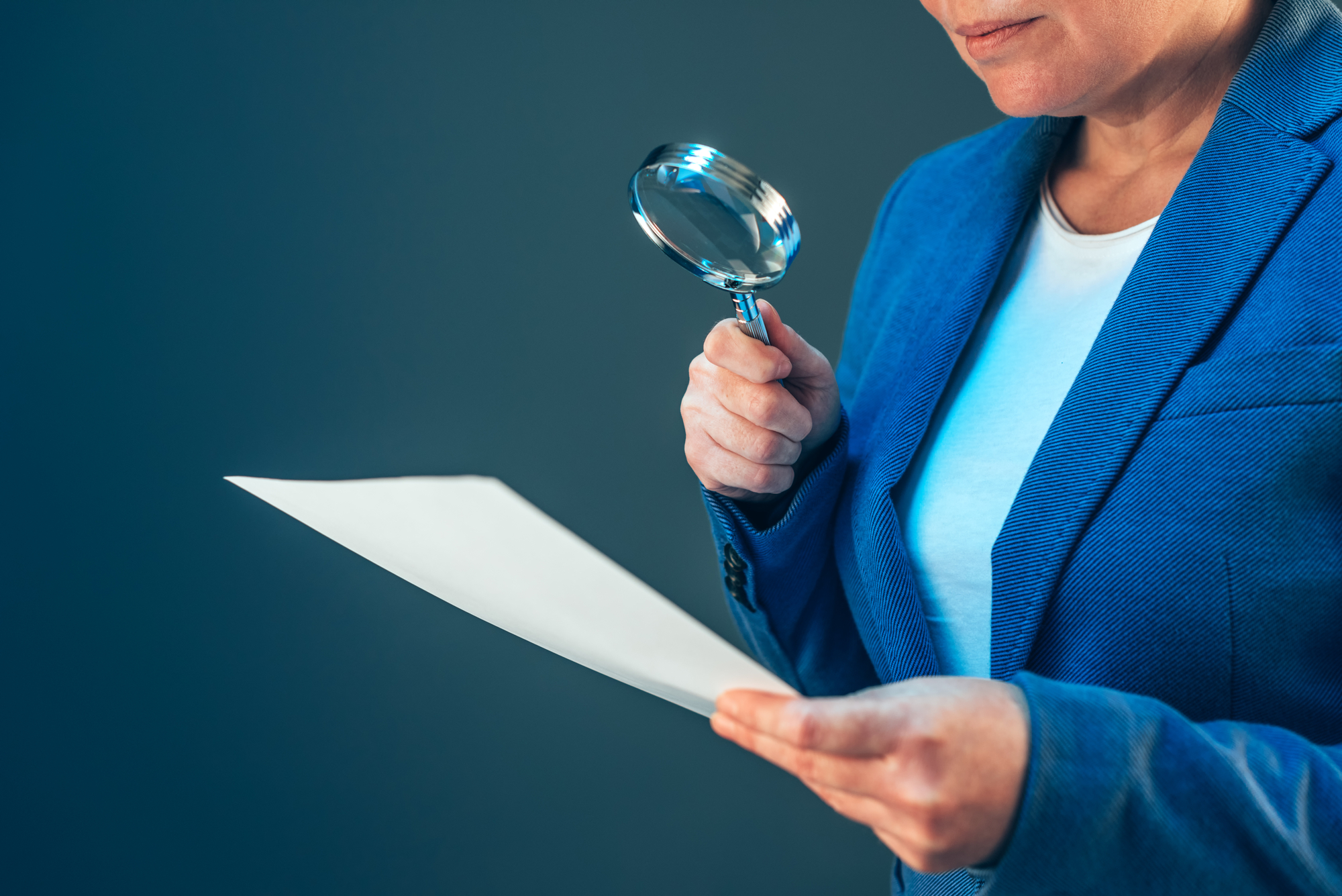 Female tax inspector looking at document with magnifying glass