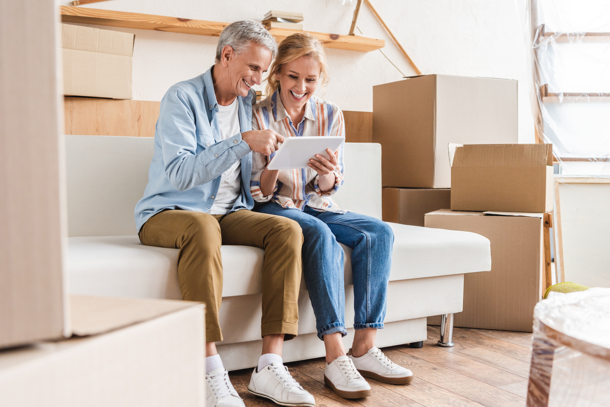 Smiling elderly couple using digital tablet while moving home