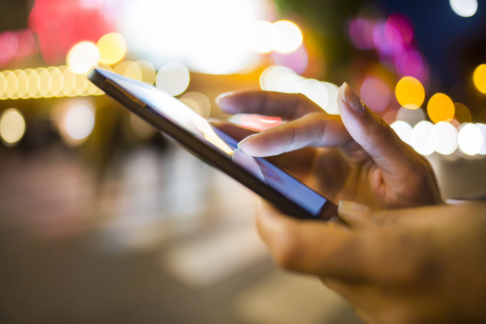 Woman using her Mobile Phone in the street, night light environment